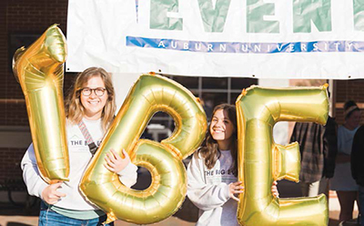 Two girls hold golden balloons during service project