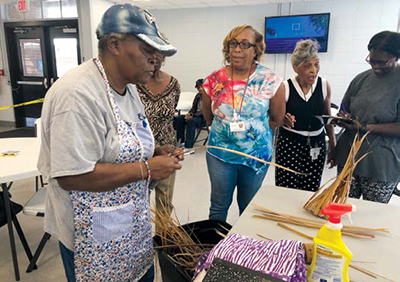 Woman demonstrates how to weave baskets while others look on