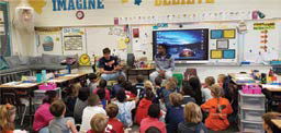 Colorful classroom with children sitting on the floor listening to someone read