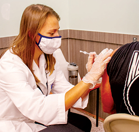 Pharmacist sticks man in arm with vaccine shot