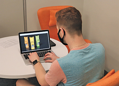 Man sits at laptop working on project with back facing the camera