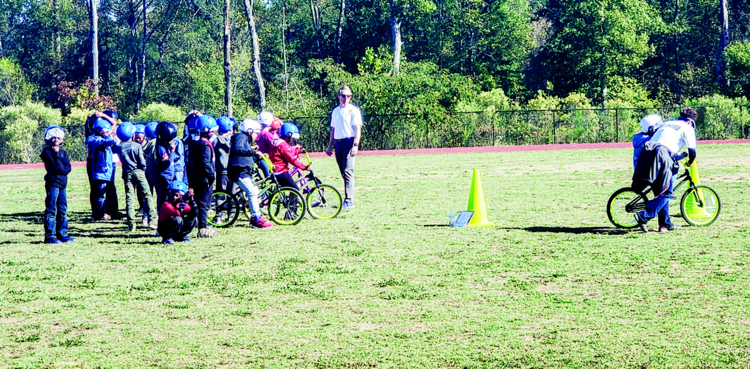 Kids on bikes ride around cone in field