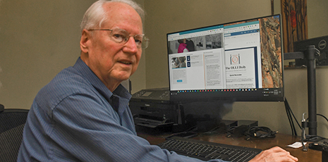 Older white man sits at laptop to demonstrate online learning.