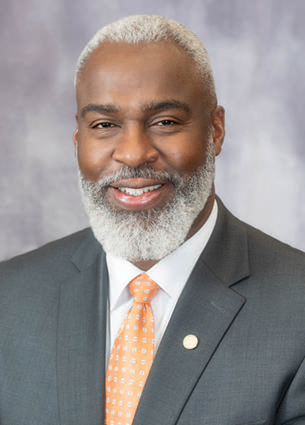 Royrickers Cook in suit with orange tie.